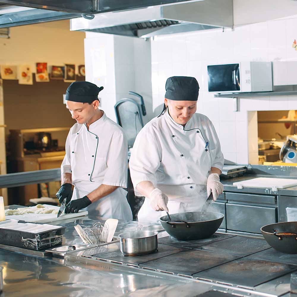 Fünf Köche in Uniform posieren in einer Küche